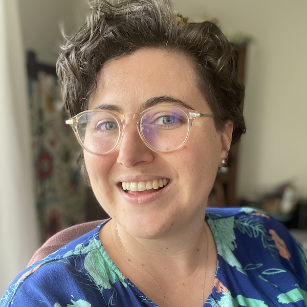 Profile picture of Marie Chatfield Rivas, smiling in a blue shirt with short hair and glasses.